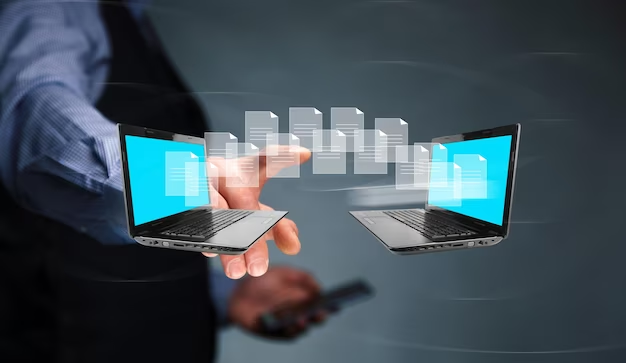A hand pointing at a graphic illustration of files being transferred from a laptop to another laptop